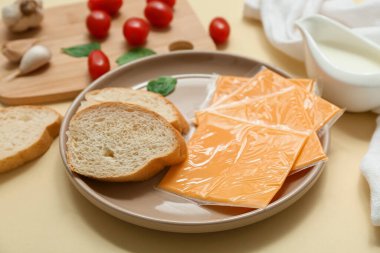 Üzerinde bej arka planda lezzetli işlenmiş peynir, ekmek ve domates dilimleri olan bir tabak. Yakın çekim.