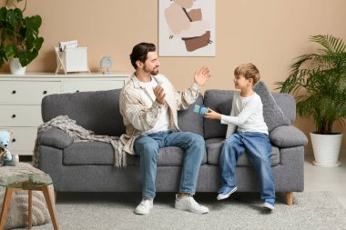 Küçük şirin çocuk, oturma odasında babasına hediye veriyor. Babalar Günü.