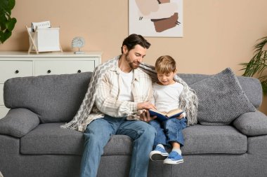 Baba ve küçük oğlu evde kitap okuyor. Babalar Günü.