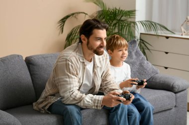 Baba ve küçük oğlu evde video oyunu oynuyorlar. Babalar Günü.