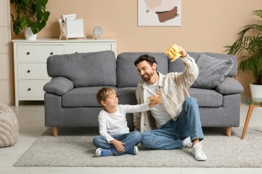 Bir adam ve küçük oğlu oturma odasında uçaklarla oynuyorlar. Babalar Günü.