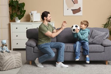 Baba ve küçük oğlu evde futbol topuyla oynuyorlar. Babalar Günü.
