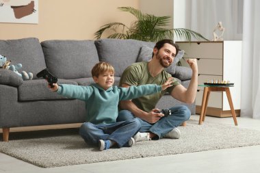 Babam ve küçük oğlu oturma odasında yerde video oyunu oynuyorlar. Babalar Günü.