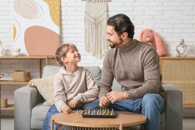 Baba ve küçük oğlu evde satranç oynuyorlar. Babalar Günü.