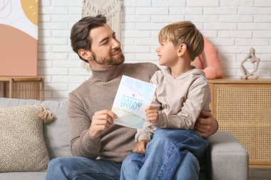 Sevimli küçük oğlan babasına tebrik kartı veriyor. Babalar Günü.