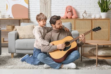 Babam ve küçük oğlu evde gitar çalıyorlar. Babalar Günü.