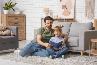 Babam ve küçük oğlu evde kitap okuyorlar. Babalar Günü.