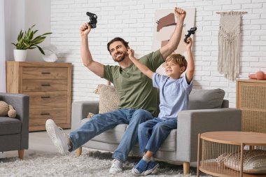 Adam ve küçük oğlu evde video oyunu oynuyorlar. Babalar Günü.