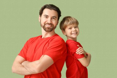 Yeşil arka planda gülümseyen baba ve oğlunun portresi. Babalar Günü.