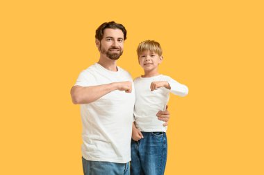 Baba ve küçük oğlu sarı arka planda yumruk tokuşturuyorlar. Babalar Günü.