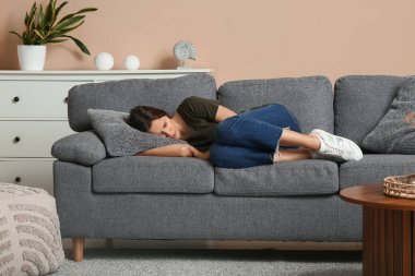 Oturma odasındaki kanepede yatan depresif genç kadın.