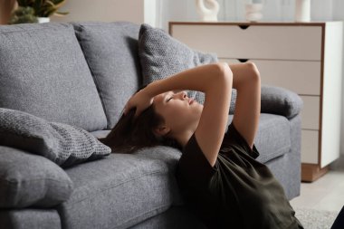 Oturma odasında depresyon geçiren genç bir kadın.