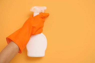 Elinde sprey şişesi olan kadın turuncu duvardan küf çıkartıyor, yakın plan.