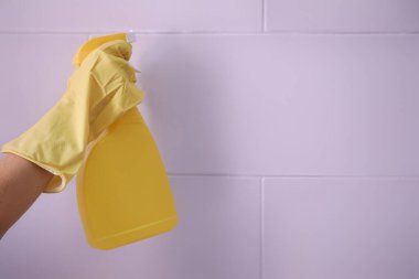 Evdeki tuğla duvardan küf temizleyen sprey şişeli kadın, yakın plan.