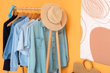 Sarı duvarın yanında elbiselerle ve şapkayla dizilin.