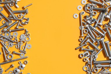 Turuncu arka planda farklı musluk cıvataları, vidalar ve krom fındıklardan yapılmış çerçeve