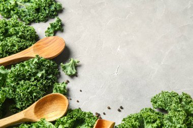 Taze lahana yaprakları, ahşap kaşıklar ve gri arka planda karabiber.