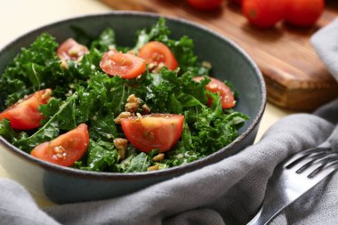 Bir kase lezzetli lahana salatası, domates, peçete ve çatal, yakın plan.