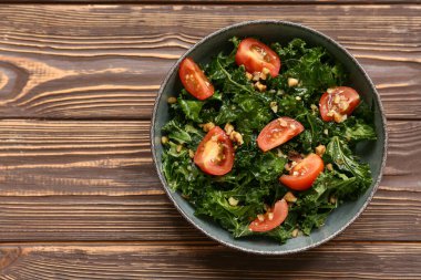 Tahta arka planda domatesli ve cevizli bir kase lezzetli lahana salatası.