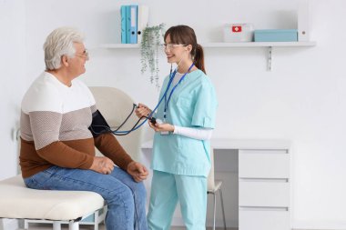 Klinikteki erkek hastanın kan basıncını ölçen genç hemşire.