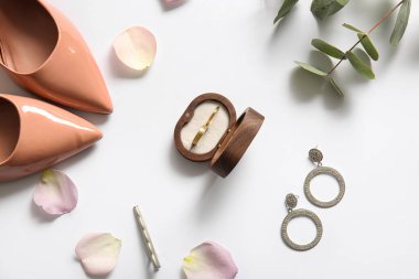 Üzerinde alyans, mücevher, topuklu ayakkabı ve gül yaprakları olan bir kutu. Üst görünüm