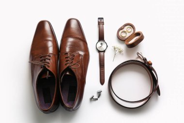 Kutuda alyanslar, ayakkabılar, kemer ve kol saati beyaz arka planda. Üst görünüm