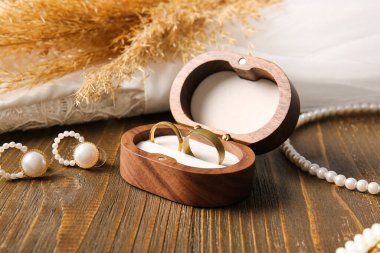 Evlilik yüzükleri kutuda, mücevherler ahşap arka planda.