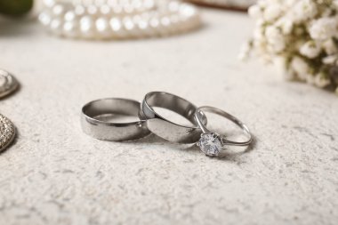 Beyaz arka planda gümüş alyanslar ve nişan yüzüğü. Yakın çekim.