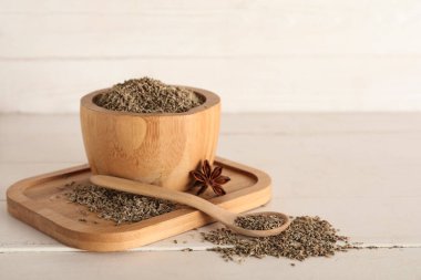 Kurumuş tohumlar, beyaz ahşap arka planda anason ve kaşık.