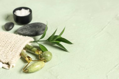 Yüz masajı aletleri, bitki dalı, spa taşları ve renk arka planında deniz tuzu