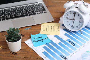 Daha sonra metin ile yapışkan notlar, Zaman Yönetimi, finansal belgeler, ahşap masa üzerindeki çalar saat ve dizüstü bilgisayar