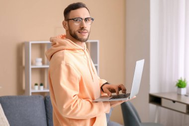 Oturma odasında dizüstü bilgisayar ile yakışıklı adam