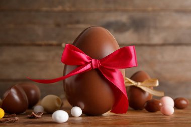 Çikolatalı yumurta, şeker ve ahşap arka planda fiyonk kompozisyonu