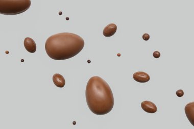 Gri arka planda uçuşan lezzetli çikolata yumurtaları.