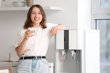 Mutfaktaki soğutucudan su içen genç kadın.