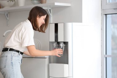 Mutfaktaki soğutucudan su içen genç kadın.