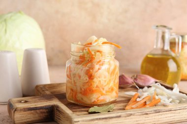 Lezzetli lahana turşulu cam kavanoz ve bej arka plandaki malzemeler. Yakın çekim.