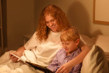 Anne ve küçük oğlu evde masal okuyorlar.