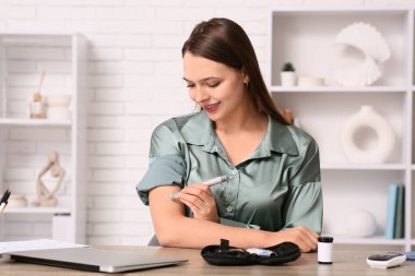 Şeker hastası kadın ofiste kendine insülin iğnesi yapıyor.