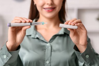 Ofiste insülin iğnesi için kalemi olan genç kadın, yakın plan.