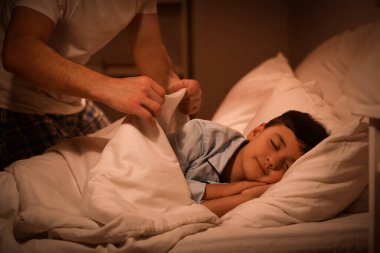 Genç baba oğlunu evde yatırıyor.