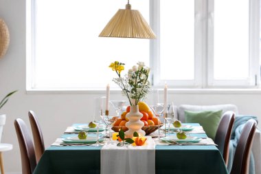 Oturma odasında turunçgiller ve yanan mumlarla dolu güzel bir masa.