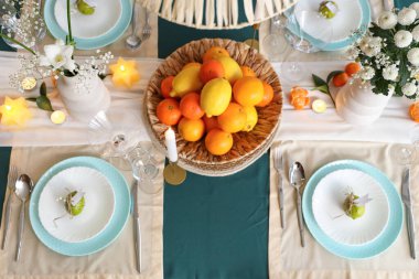 Odasında taze narenciye ve çiçek olan şık bir masa. Üst görünüm