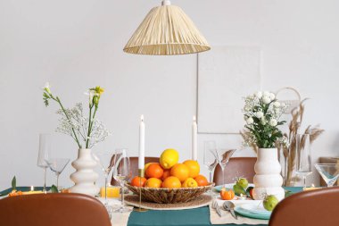 Oturma odasında turunçgiller ve yanan mumlarla dolu bir masa.