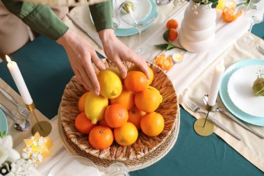 Yemek masasını bir kase narenciye ile süsleyen kadın elleri. Yakın çekim.