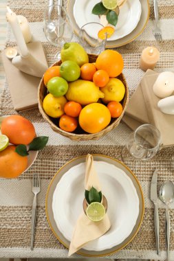 Turunçgiller ve yanan mumlarla süslü bir masa. Yakın çekim.