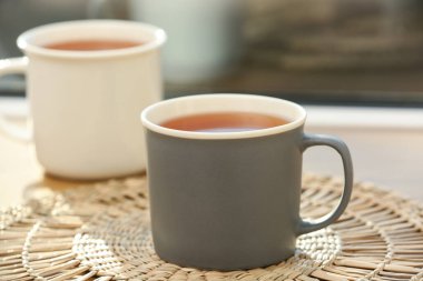 Pencereye karşı hasır üzerinde sıcak siyah çay fincanları. Yakın çekim.