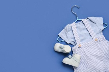 Şık bebek kıyafetleri ve mavi arka planda çorapları olan bir askı.