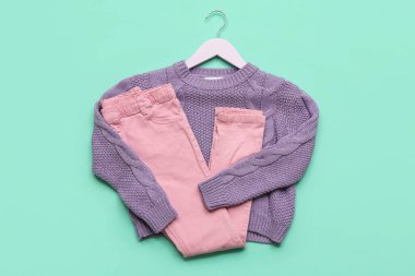 Süslü çocuk süveteri ve renkli pantolonu olan askı