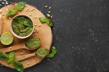 Bir kase dolusu lezzetli pesto sosu ve siyah grunge arkaplan içeriği.